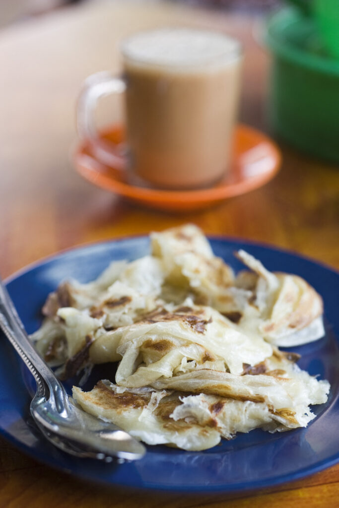 Typical Malaysian breakfast, roti canai and cup of teh tarik.