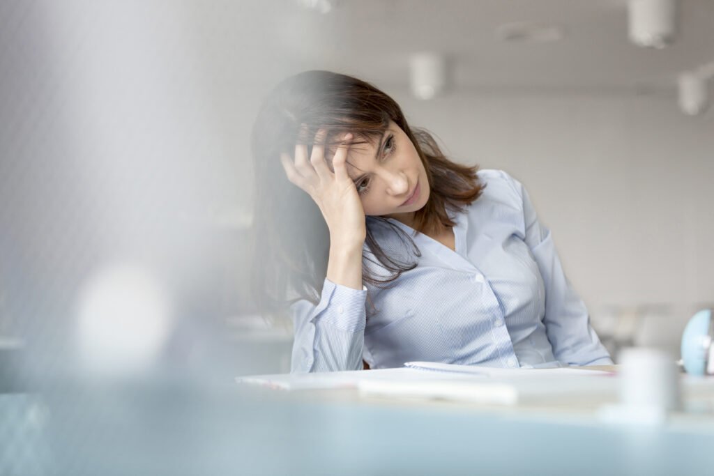 Tired businesswoman with head in hands looking away.