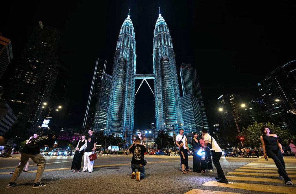 Photographers taking photos of tourists in front of the PETRONAS Twin Towers in Kuala Lumpur.